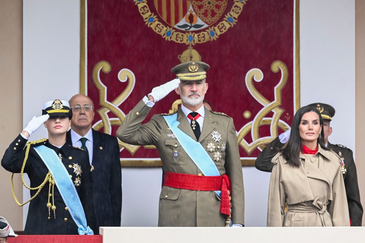 ​Letizia, de rojo y con gabardina, y Leonor, con uniforme de guardamarina, desafían a la lluvia en el desfile militar del Día de la Hispanidad 